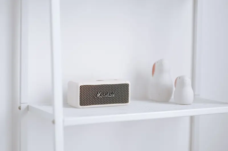 A stylish setup featuring a Marshall wireless speaker and minimalist decor on a white shelf