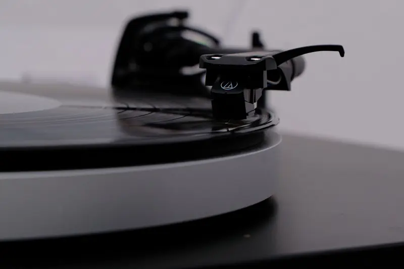 A detailed close-up of a vinyl turntable record needle, evoking a sense of classic music nostalgia
