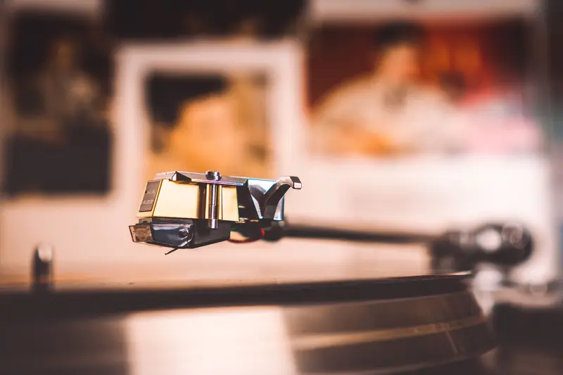 Close-up shot of a vintage vinyl record player needle with blurred background, emphasizing nostalgia
