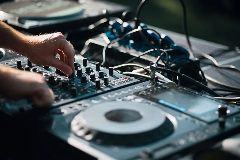 Close-up of a DJ mixing music on a turntable outdoors, capturing the art of sound mixing