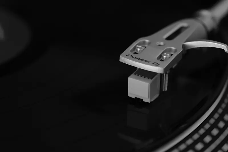 High-quality close-up of a turntable's tonearm on a vinyl record, highlighting DJ equipment