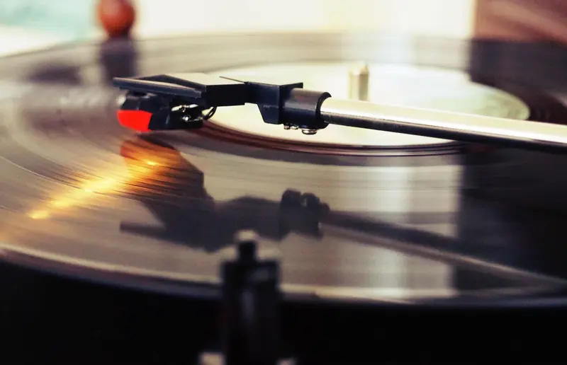 Detailed view of a spinning vinyl record on a turntable with a stylus playing the music