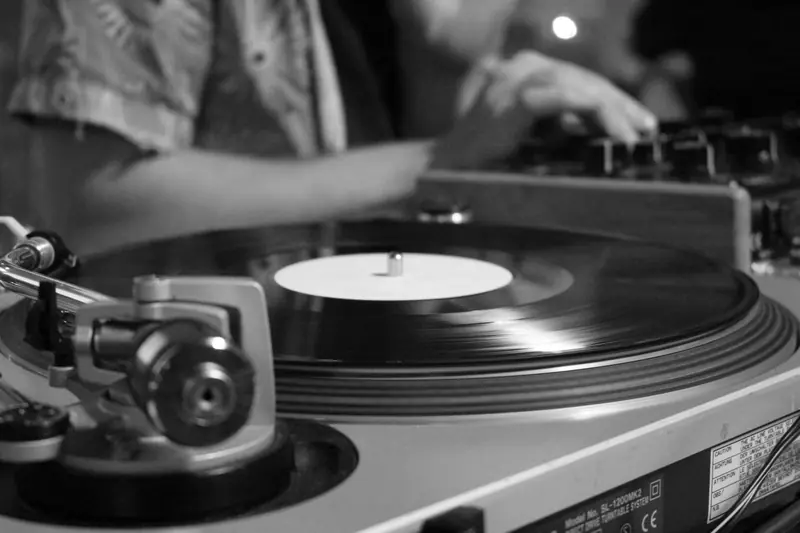Black and white image of a spinning vinyl record on a turntable, blending classic and modern music vibes