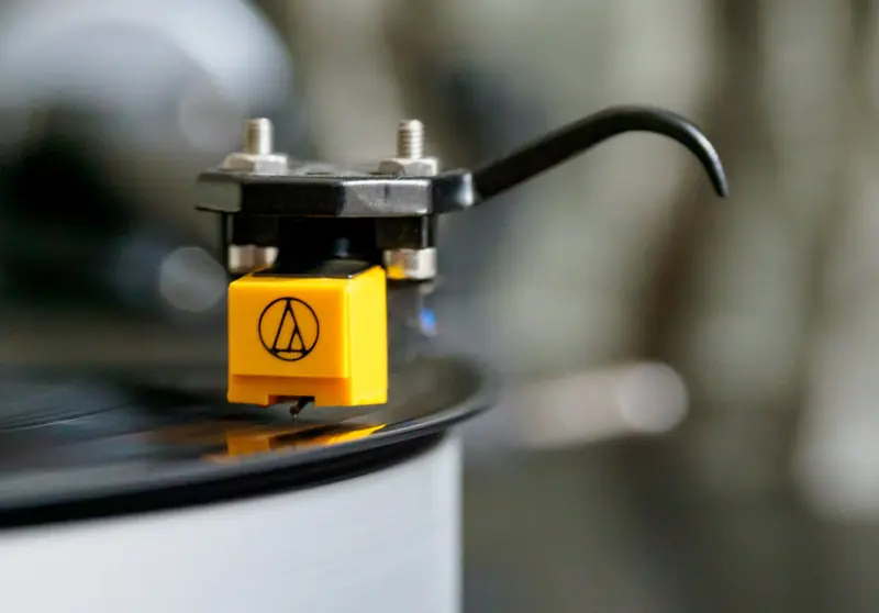 Detailed close-up image of a turntable stylus on a spinning vinyl record, showcasing analog music technology