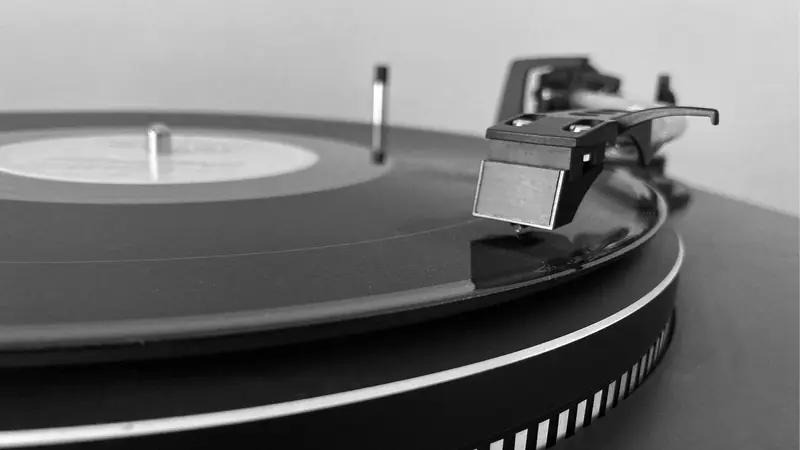 Close-up of a classic vinyl record playing on a turntable in grayscale