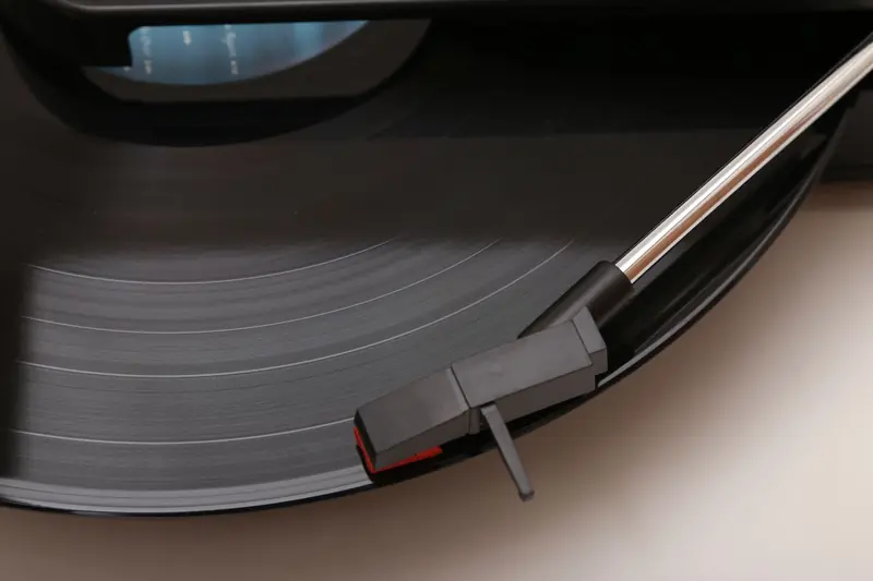 Detailed view of a vinyl record playing on a modern turntable, highlighted tonearm