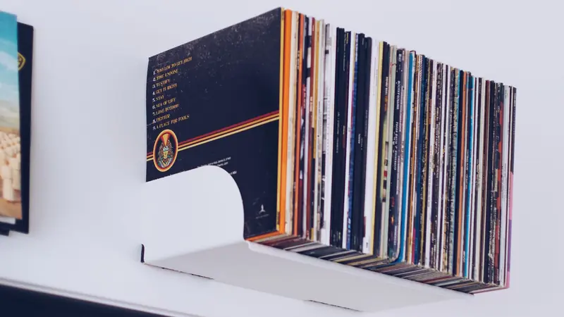 A neat stack of vinyl records on a minimalist white wall shelf