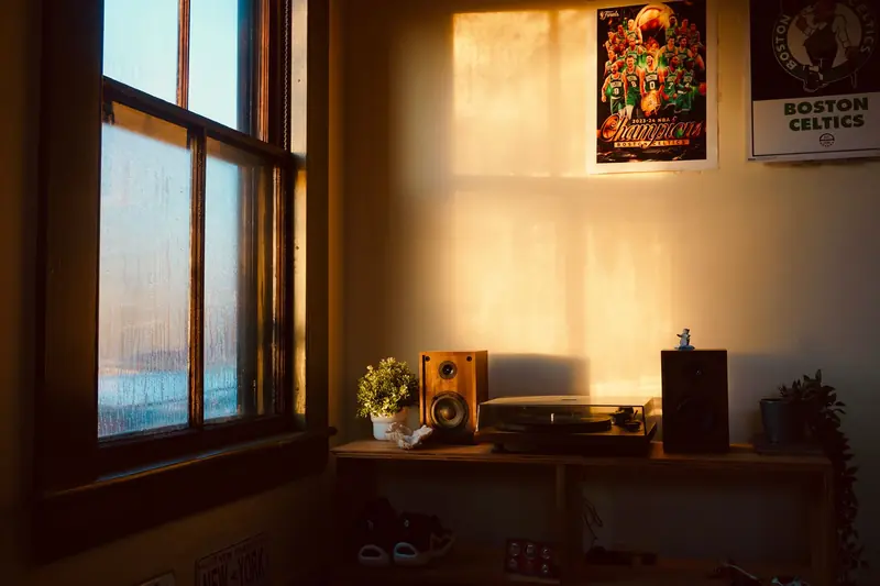 A warmly lit room featuring vintage speakers, a turntable, and basketball posters, creating a nostalgic ambiance